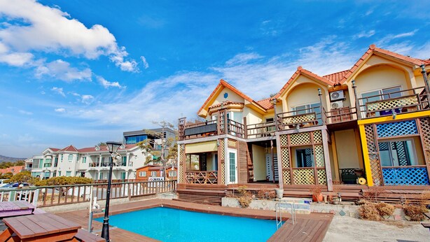 Zona residencial com piscina, várias casas com varandas e céu azul e límpido.