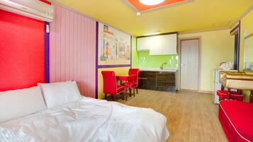 Una habitación de hotel con cama, una pequeña mesa de comedor con sillas, kitchenette y baño.