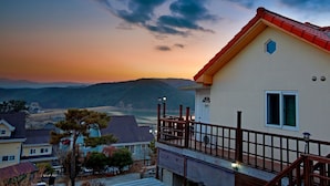 Uma casa com varanda com vista para um lago e montanhas.