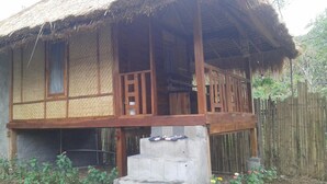 Una casa tradicional con techo de paja, balcón de madera y base de hormigón.