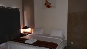 Un dormitorio con cama, mesita de noche, lámpara y un cuadro en la pared.