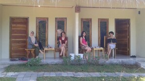 Un espacio de estar al aire libre cubierto con puertas y ventanas de madera, una mesa con objetos y un techo de paja.