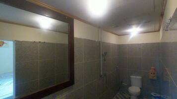 Un baño con un espejo grande, un lavamanos, un inodoro y una ducha.