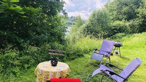 An outdoor seating area with a round table, two chairs, and a small grill. - Tranquil Lakeside Cottage Retreat (Avesta)