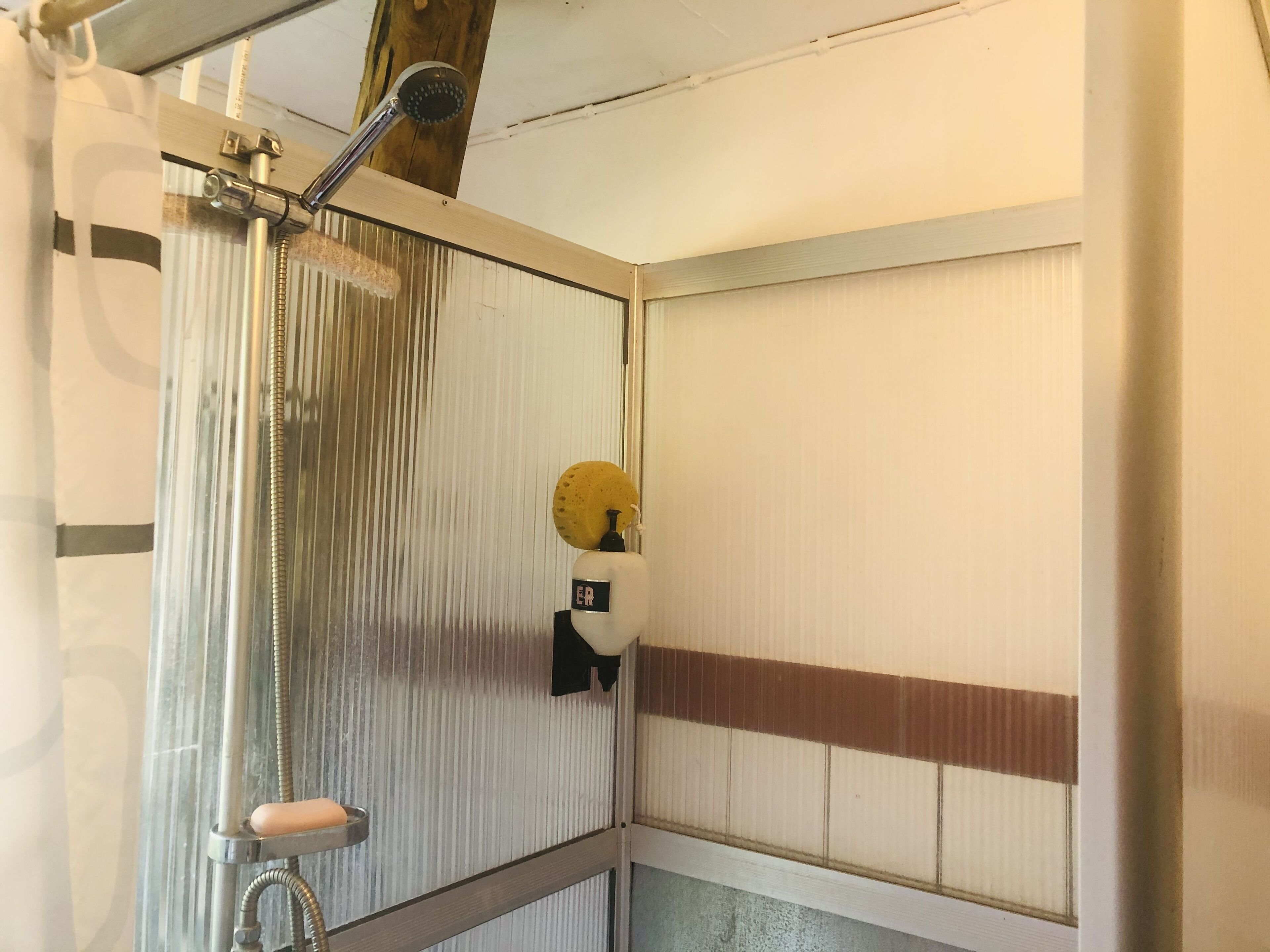 A bathroom with a shower, a towel rack, and a towel hanging on the wall.