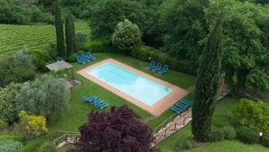 A rectangular swimming pool surrounded by a lawn with several lounge chairs. - Cosy apartment in villa for 7 guests with WIFI, pool, TV, patio and pets allowed (Greve In Chianti)