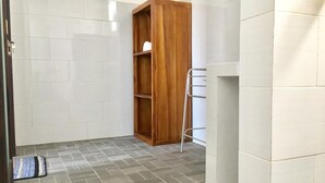 A bathroom with a wooden cabinet, a towel rack, and a tiled floor. - Gangga Guesthouse (Canggu)