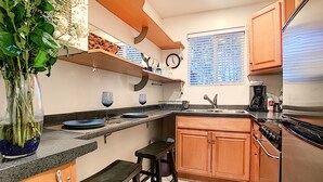 A compact kitchen with a built-in oven, a sink, and a small bar area.