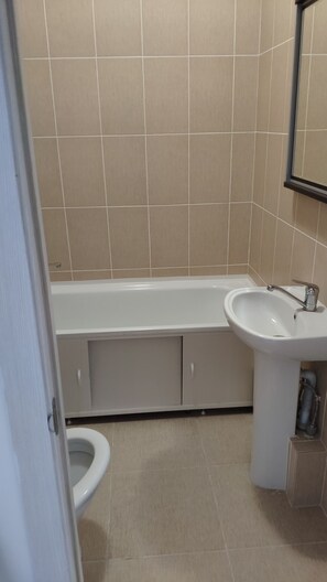 Un baño con bañera, lavamanos e inodoro.