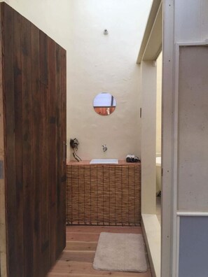 A narrow hallway with a wooden door, a small round mirror, a sink with a towel, and a small rug. - Kyoto style small inn iru (Kyoto)