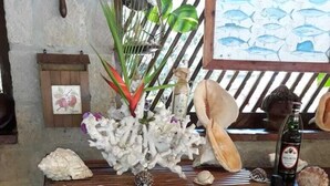 A wooden shelf with various seashells and a bottle of liquor.