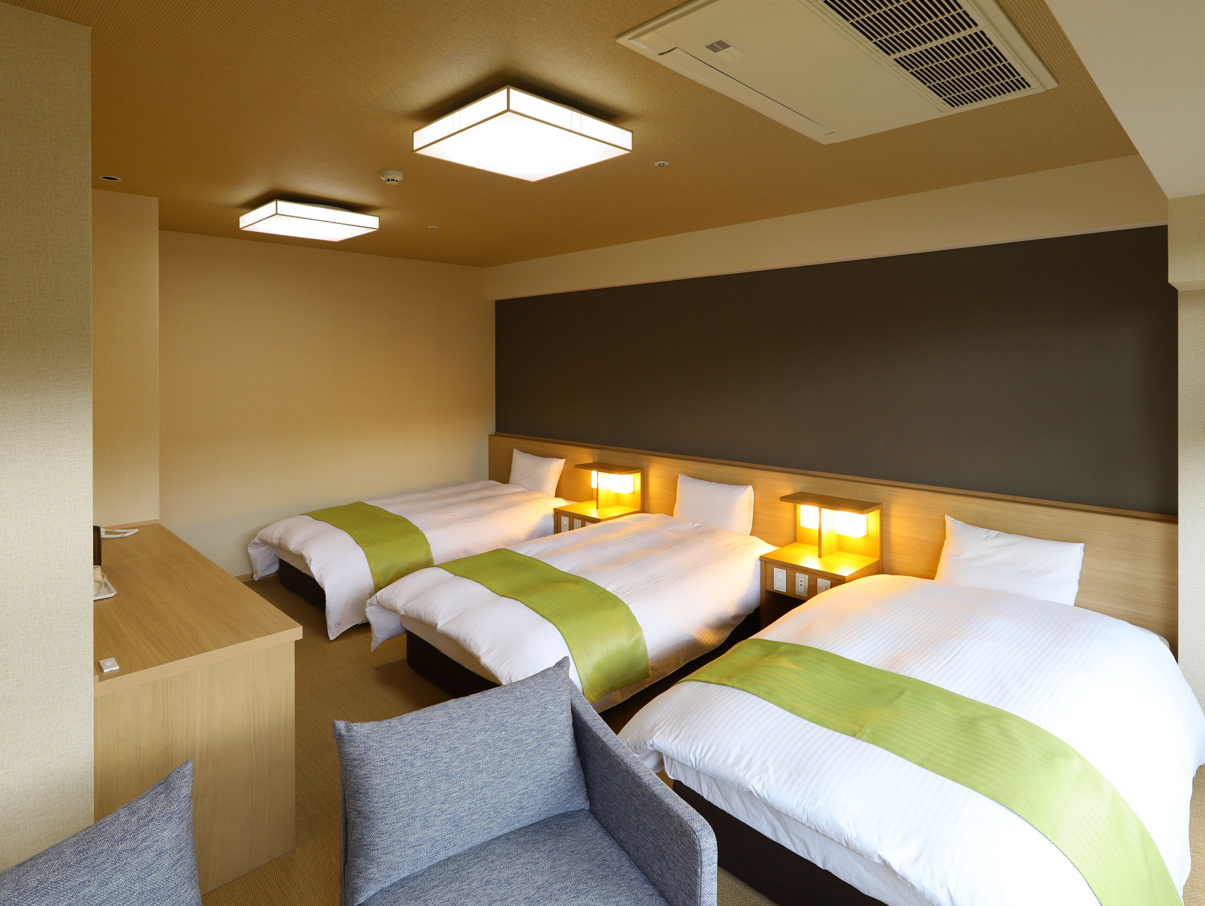 A hotel room with two beds, a desk, and a chair.