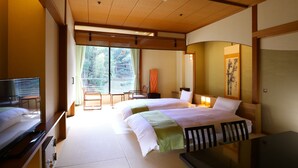 A hotel room with a bed, bedside tables, a TV, and a view of the outdoors.