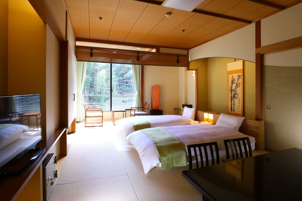 Une chambre d’hôtel avec un lit, des tables de chevet, une télévision et une vue sur l’extérieur.