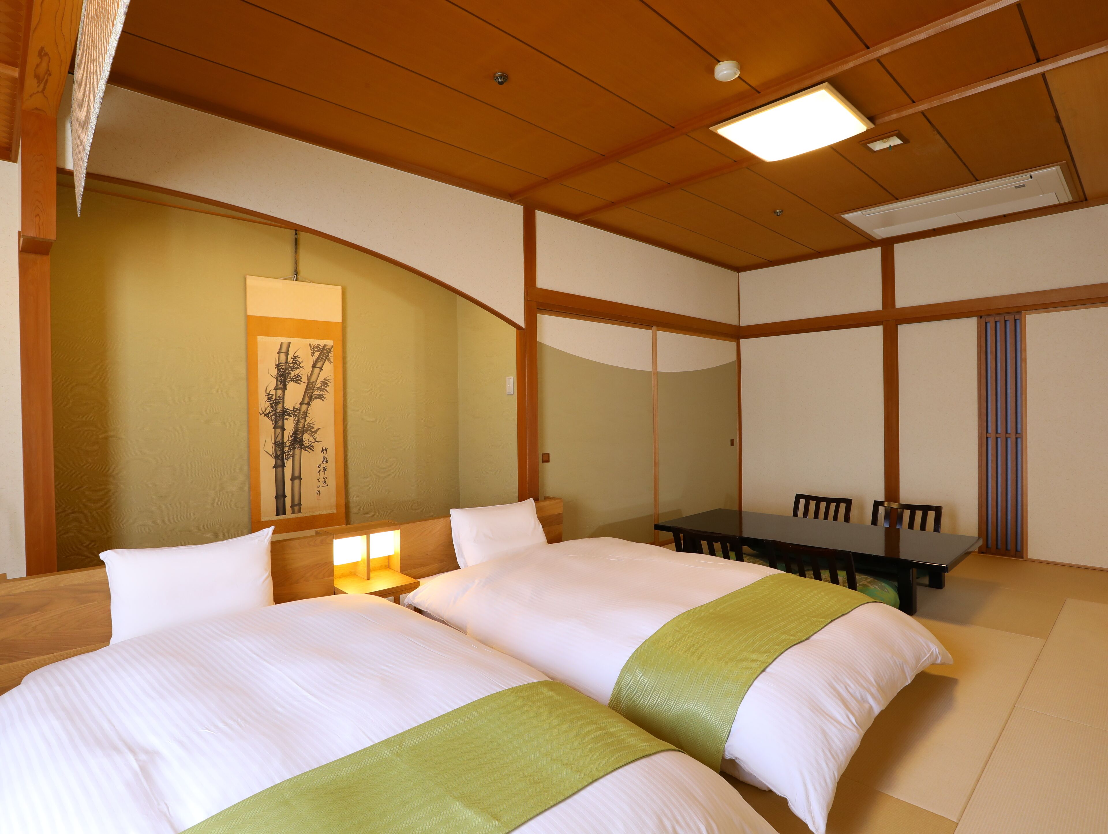 Una habitación de hotel con dos camas, una mesa de comedor y una pintura tradicional al estilo japonés en la pared.