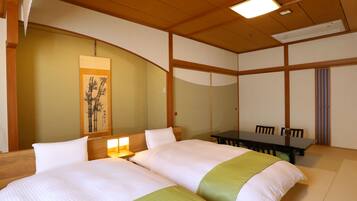Una habitación de hotel con dos camas, una mesa de comedor y una pintura tradicional al estilo japonés en la pared.