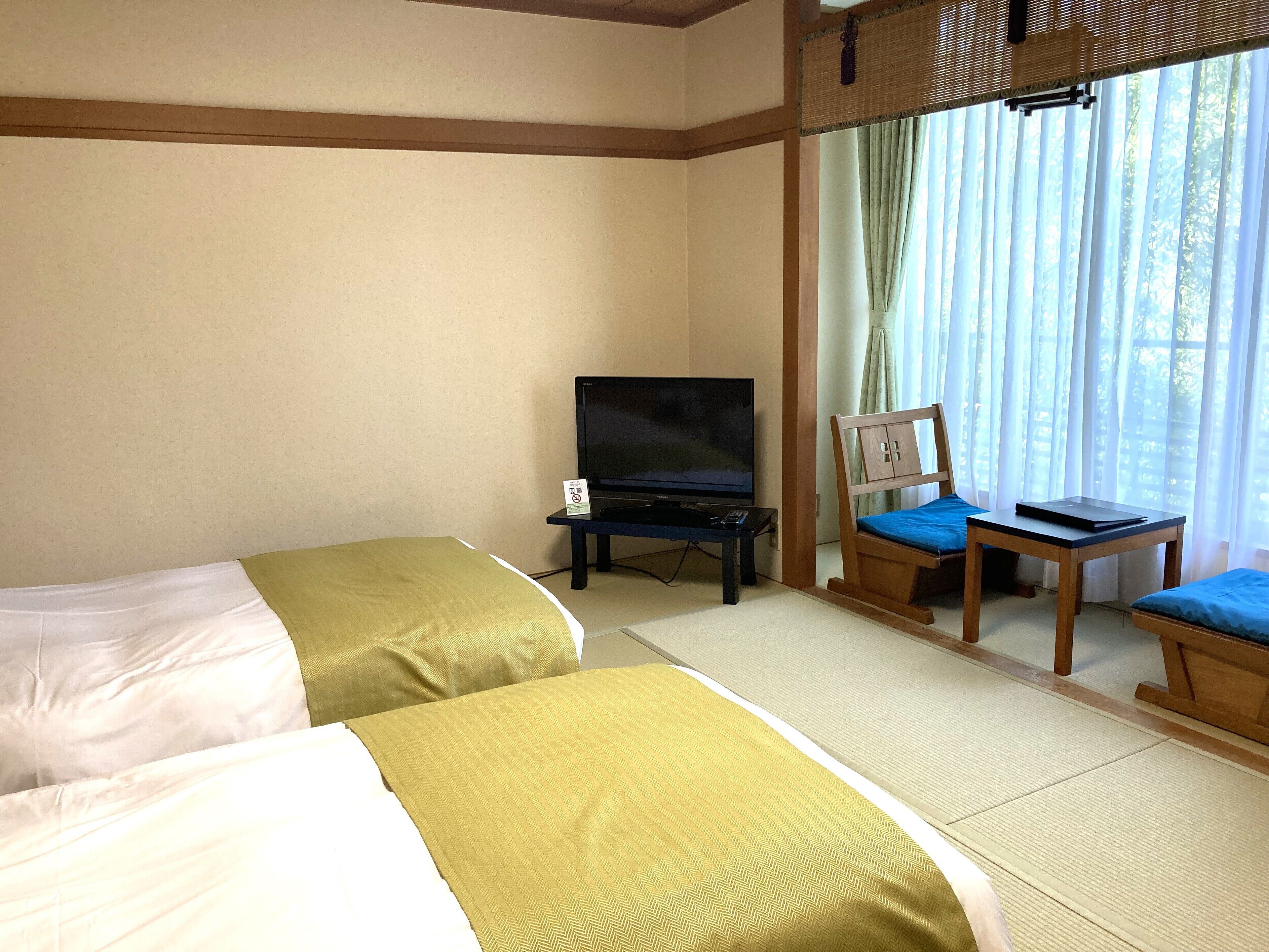 A hotel room with two beds, a television, and a small table with a chair.