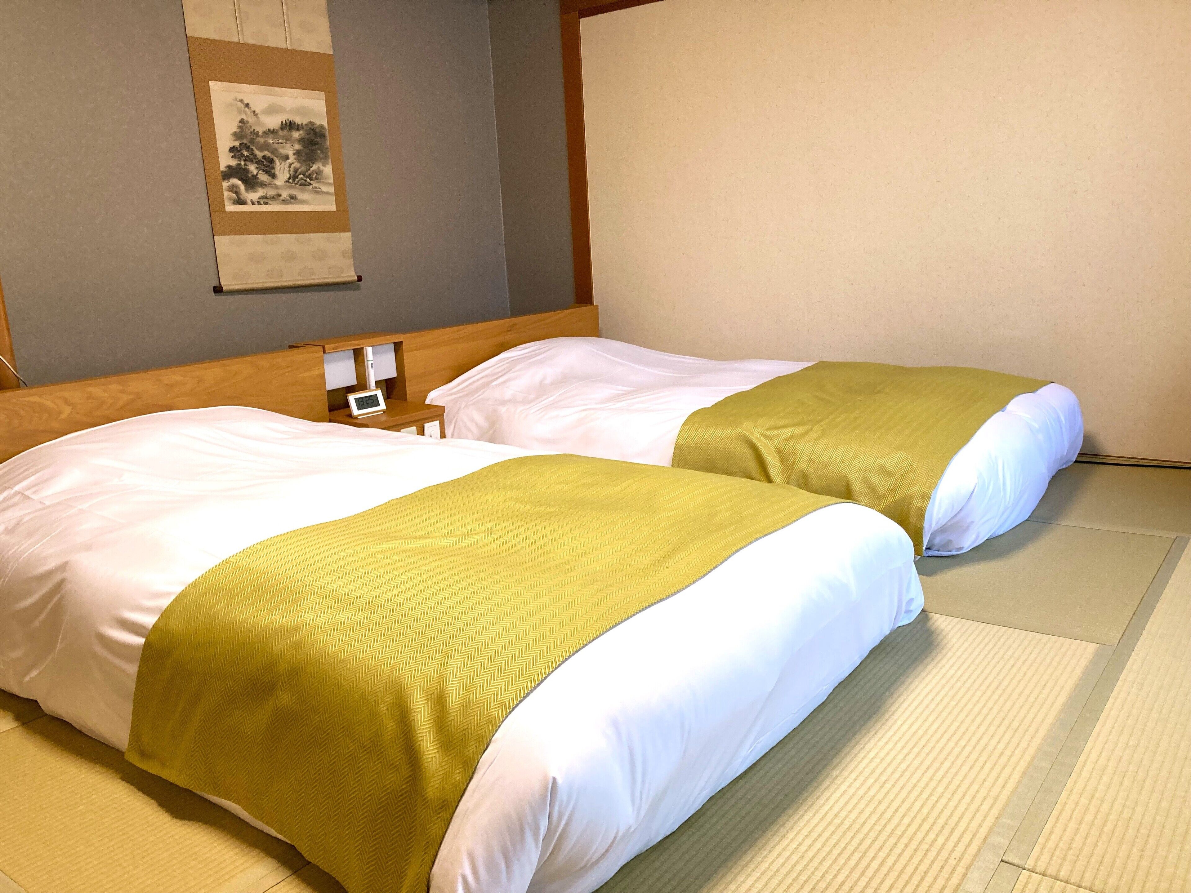 A hotel room with two beds, each with white linens and a green accent.