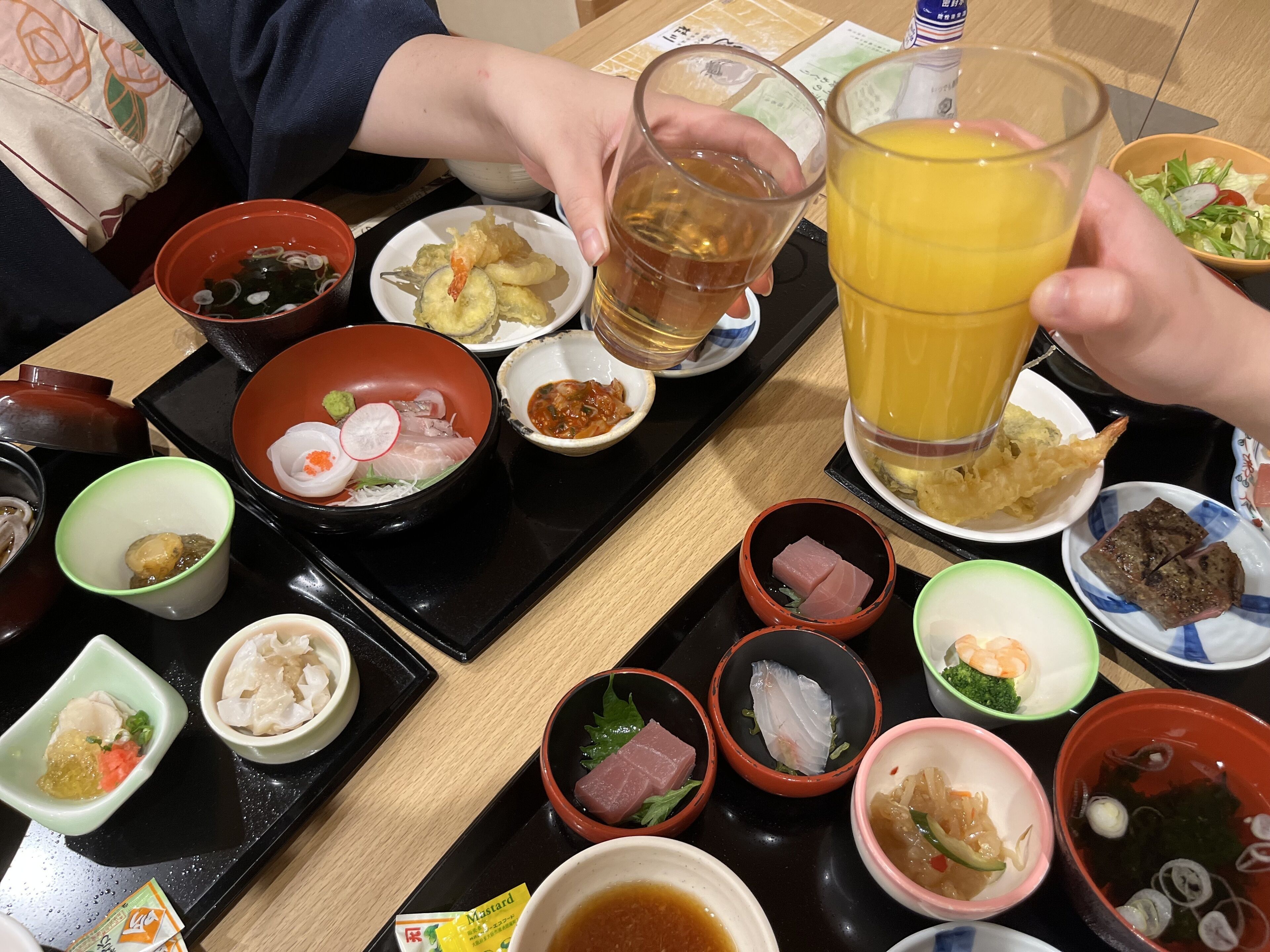 Una mesa con diversos platos, entre ellos mariscos, verduras y un vaso de zumo de naranja.