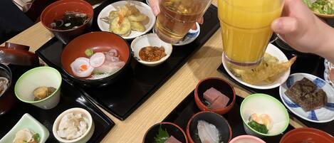 A table with various dishes, including seafood, vegetables, and a glass of orange juice.