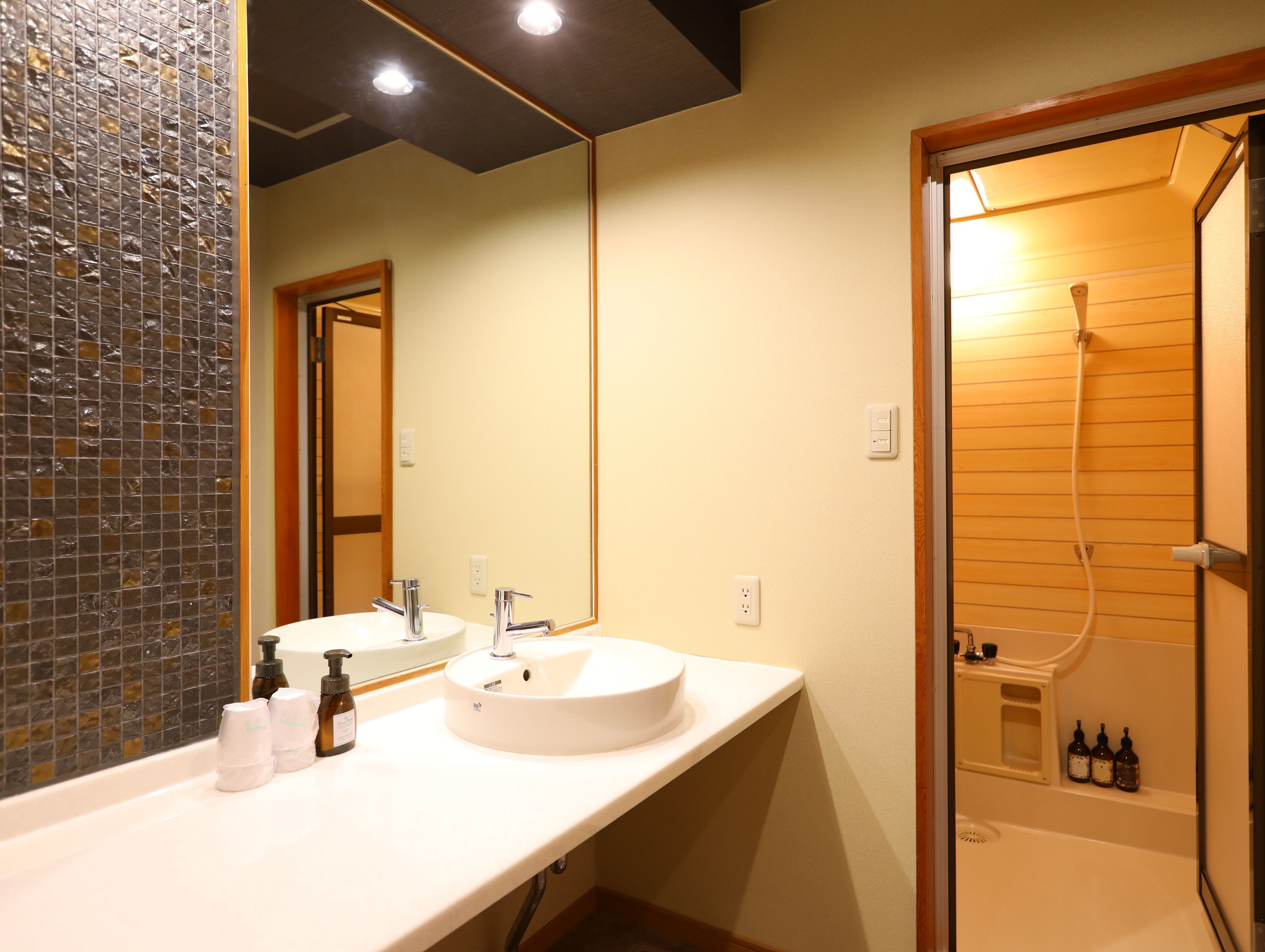 A bathroom with a white sink, two faucets, a mirror, and a shower area.