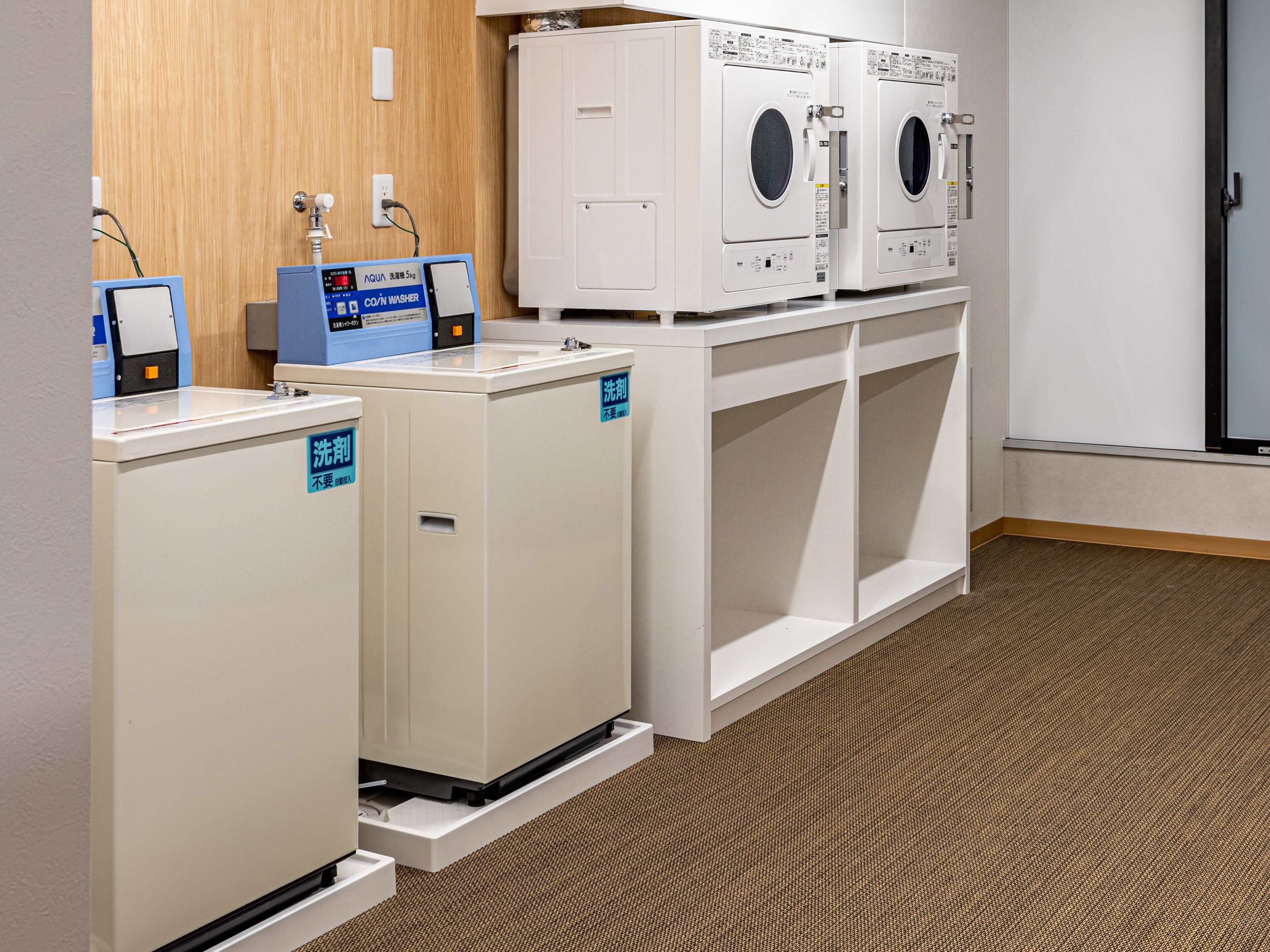 A laundry area with two washing machines and a dryer, a scale, and a water dispenser.