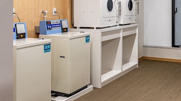 A laundry area with two washing machines and a dryer, a scale, and a water dispenser.