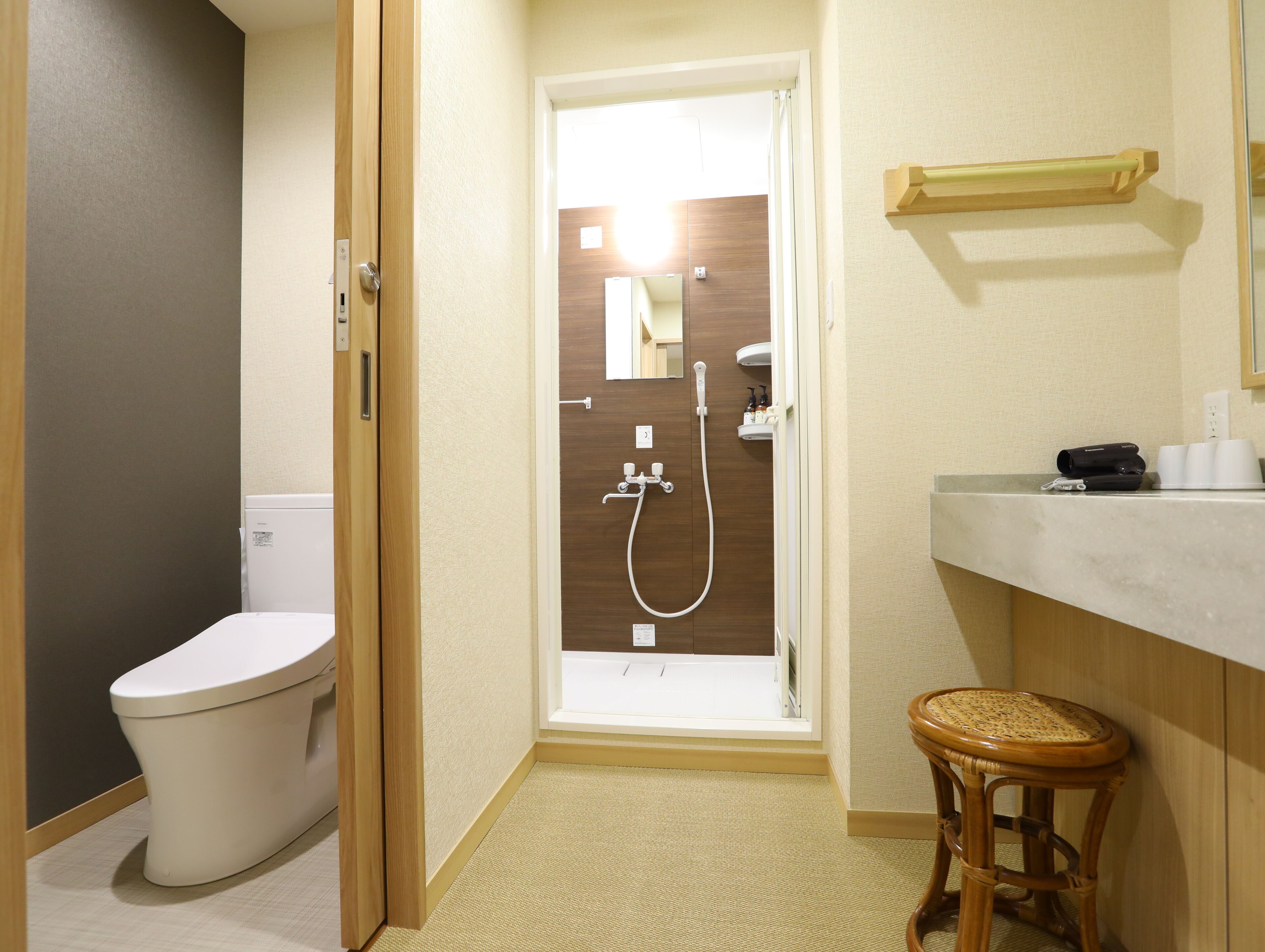 A bathroom with a toilet, shower, and a small stool.
