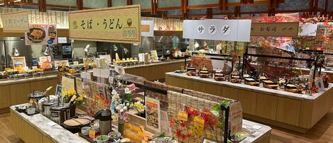 A buffet area with various food stations, including a sushi bar and a section for bread and pastries.