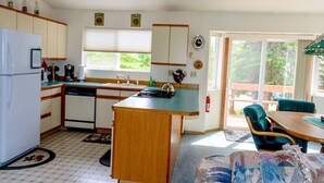 A compact kitchen with a central island, a refrigerator, a dishwasher, and a window providing natural light. - Alaskan Cozy Home for the Whole Family and Friends (Sterling)