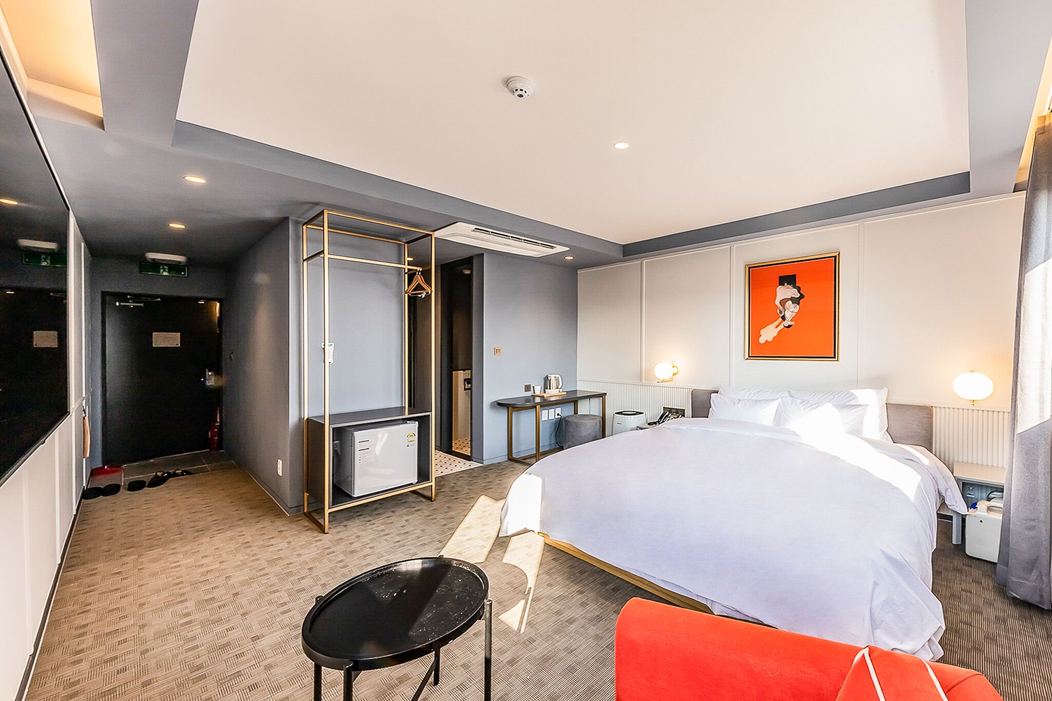 Habitación de hotel con una cama grande, un escritorio, una silla, un armario y baño.