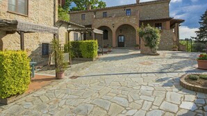A stone courtyard with a central building featuring arches and a tiled roof. - Lovely apartment in villa for 2 people with WIFI, pool, TV and patio, close to San Gimignano (Volterra)