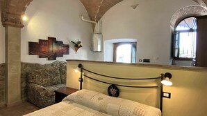 A bedroom with a bed, a sofa, a mirror, and a window. - Lovely apartment in villa for 2 people with WIFI, pool, TV and patio, close to San Gimignano (Volterra)