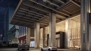 Un bâtiment moderne doté d’un porche, de grandes colonnes et d’une voiture garée devant.