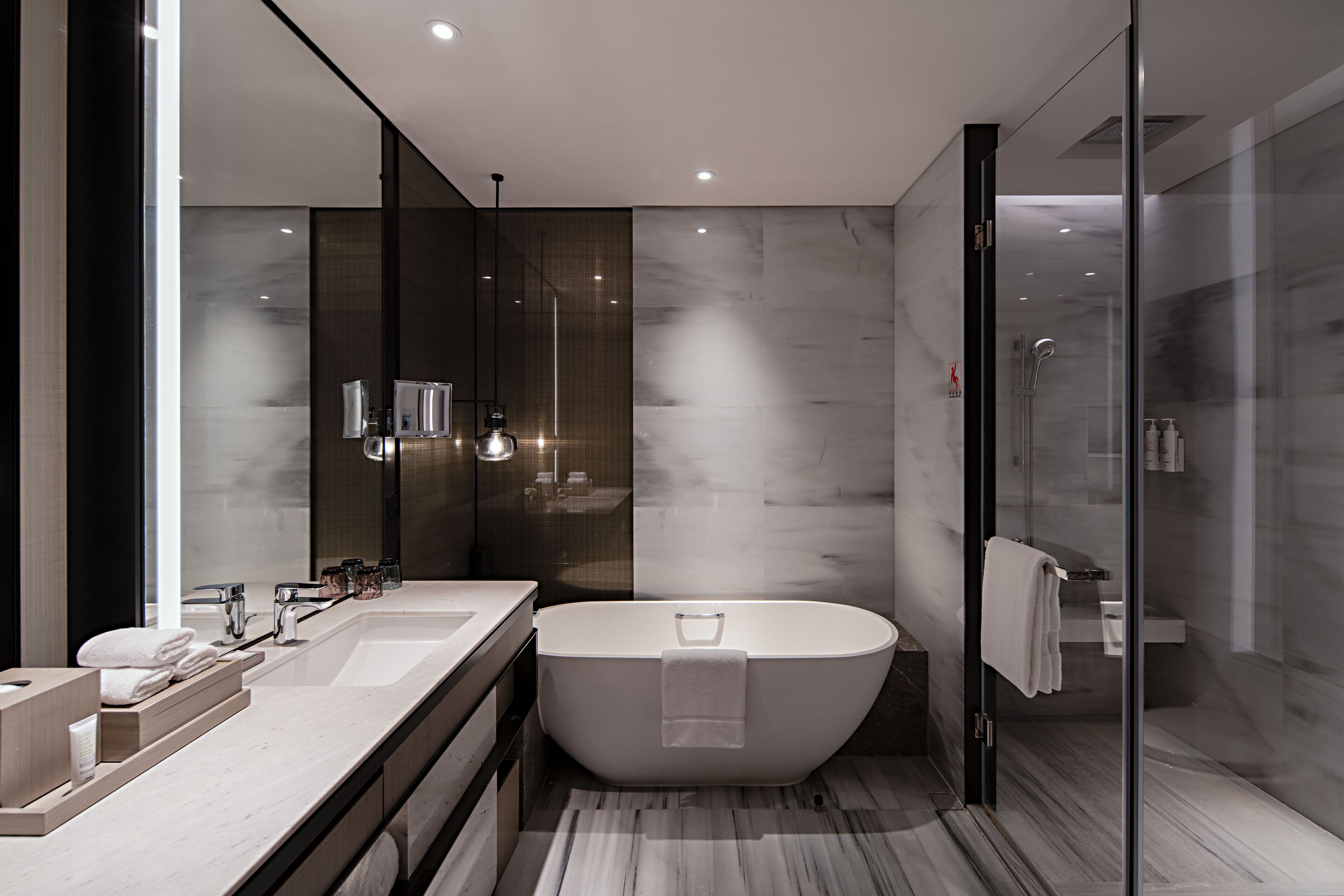 A modern bathroom with a freestanding bathtub, dual sinks, and a glass shower enclosure.