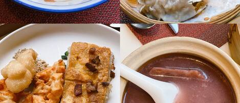 Une table à manger avec un bol de nouilles, une assiette de raviolis, un plat de poisson et de raviolis, et un bol de soupe.