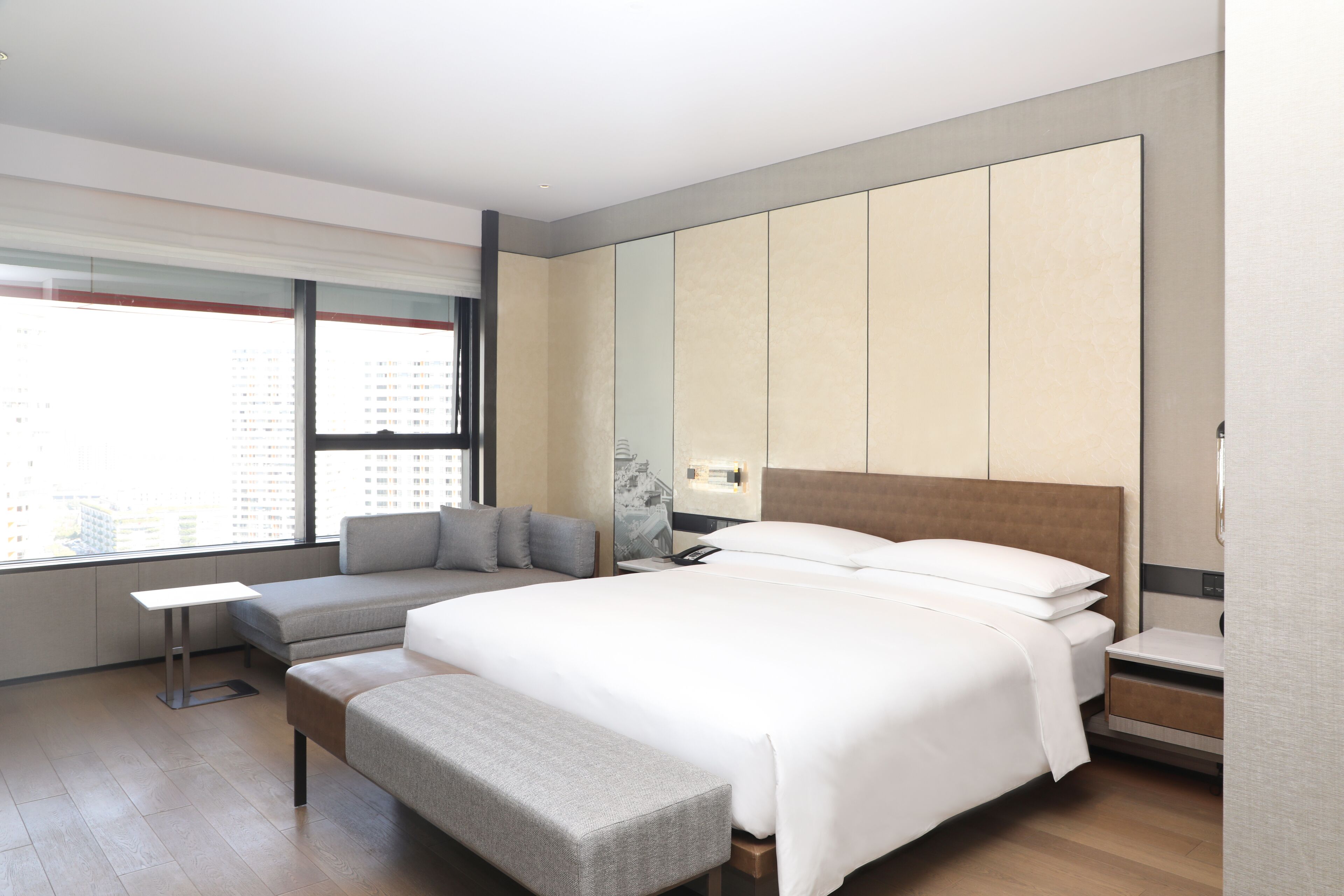 Habitación de hotel moderna con una cama grande, una zona de estar y vistas a la ciudad.