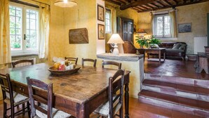 A rustic dining area with a wooden table, chairs, and a fruit bowl. There is a staircase leading to a living area with a sofa and a lamp. - Beautiful private villa for 5 people with WIFI, TV, patio and pets allowed, close to Viareggio (Camaiore)