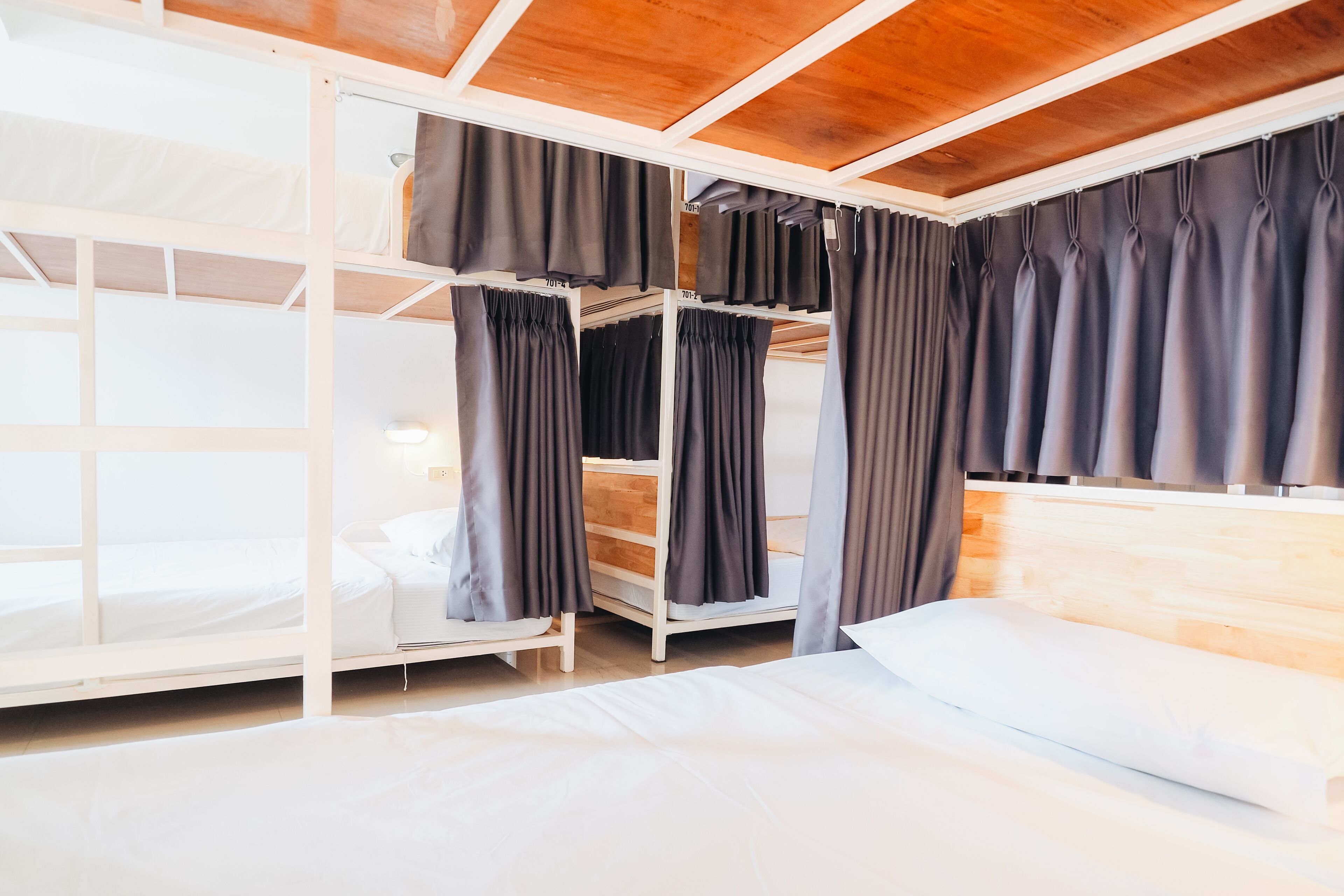 A bunk bed room with a wooden ceiling and a white bed.