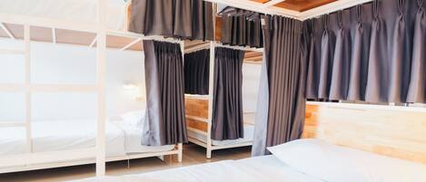 A bunk bed room with a wooden ceiling and a white bed.