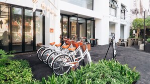 A modern building with a glass entrance, outdoor seating, and a row of bicycles with orange seats. - Loyy Hotel - Hostel (Chiang Mai)