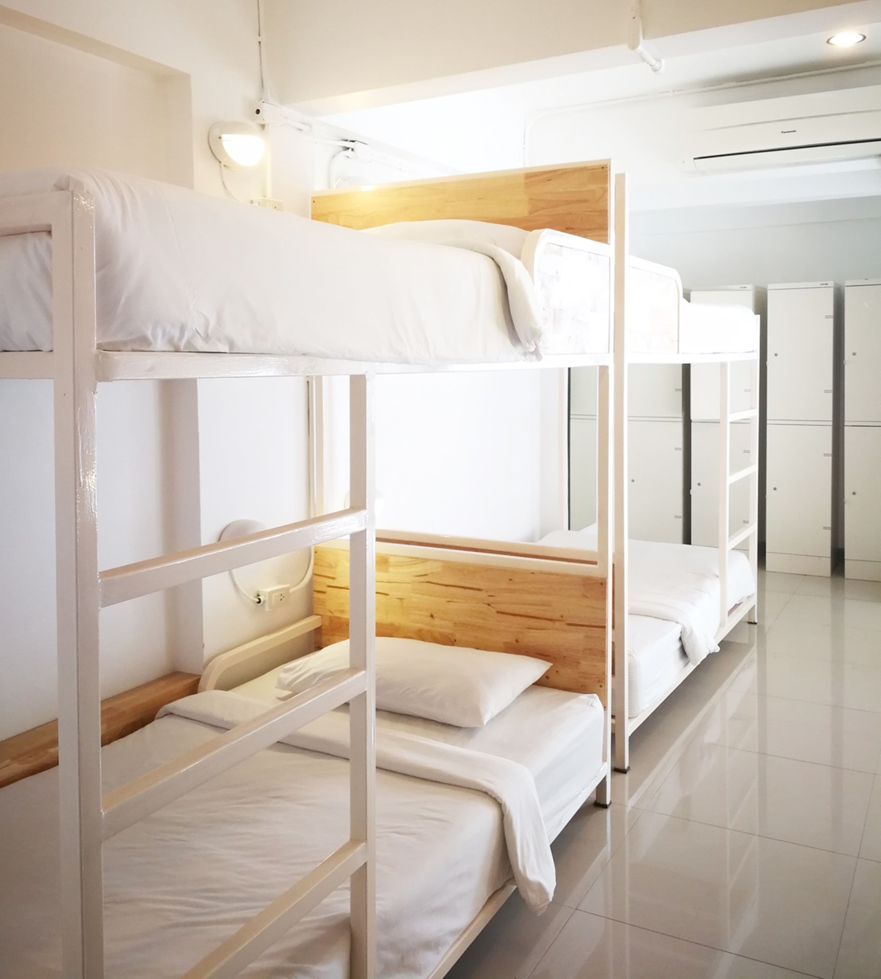 A bunk bed room with white bedding and wooden headboards.
