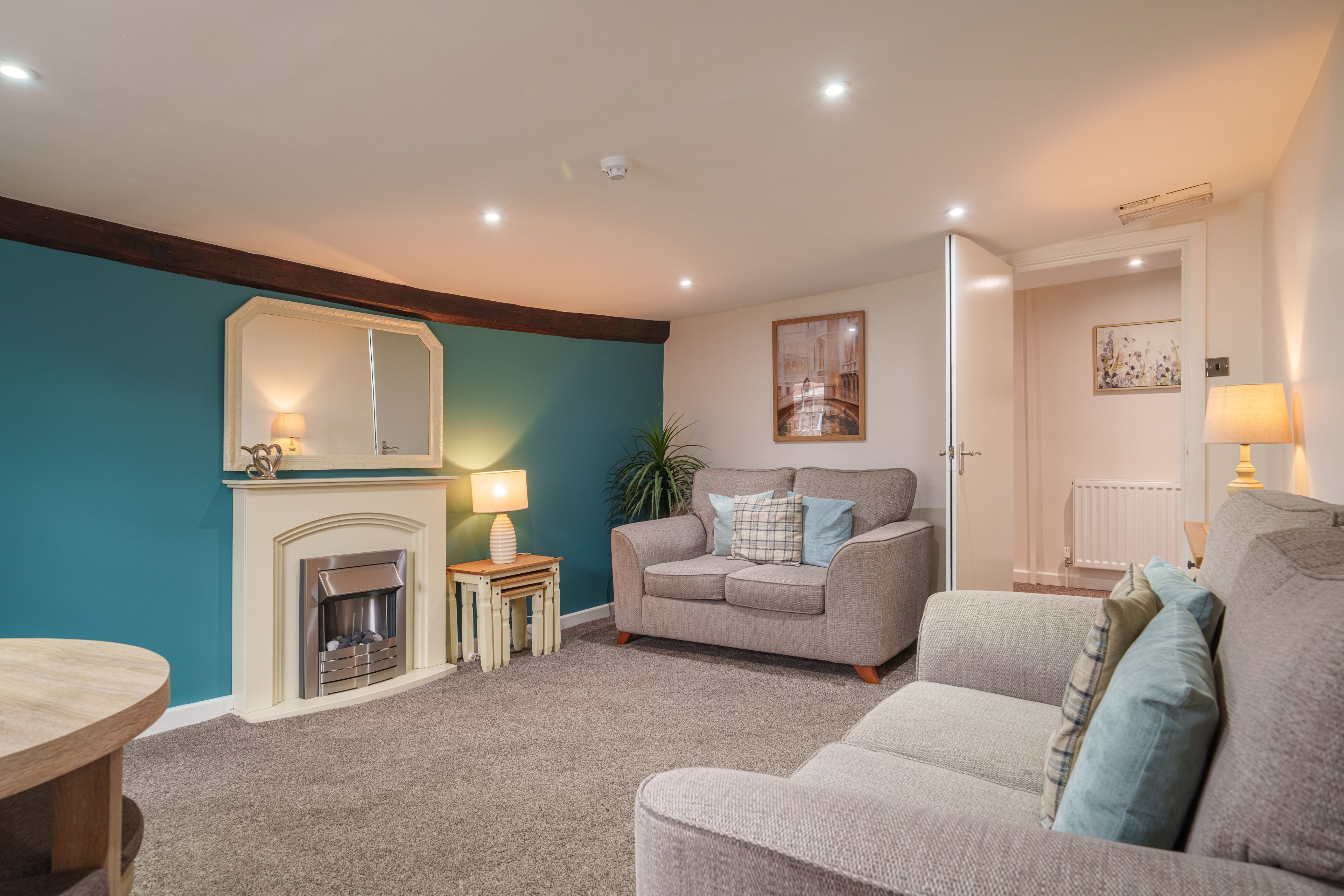 A living room with a fireplace, a sofa, a small table, and a lamp.