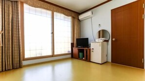 Ein Zimmer mit einer Schiebeglastür, einem Fernseher auf einem Holzboden, einem kleinen Kühlschrank und einer Holztür.