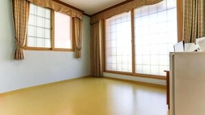 Ein Zimmer mit zwei großen Fenstern, Holzzierleisten und einem weißen Kühlschrank.