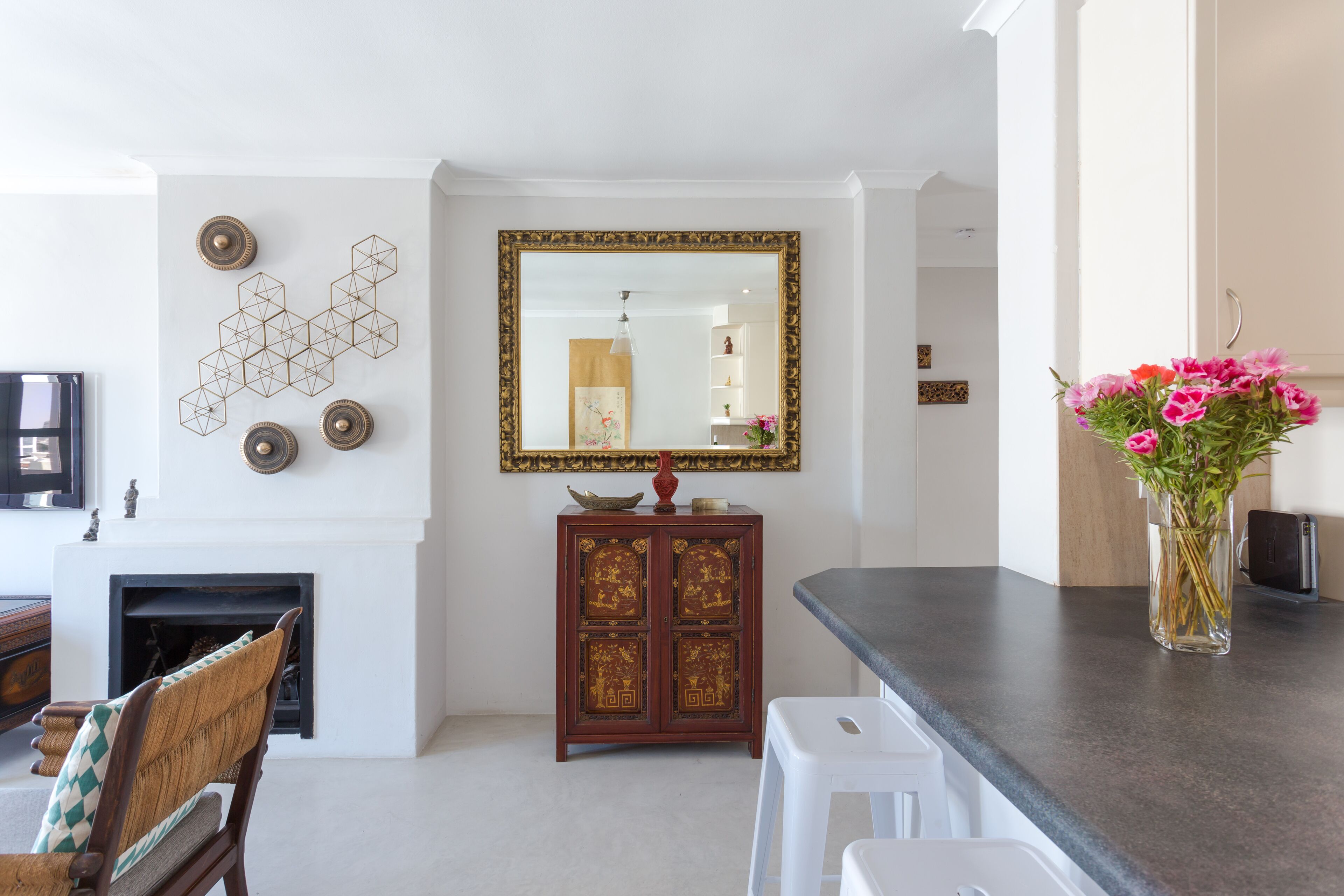Ein Wohnzimmer mit Kamin, einem Spiegel und einer Vase mit Blumen auf der Anrichte.