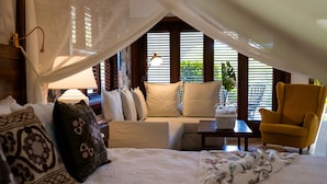A bedroom with a canopy bed, a sofa, a yellow armchair, and a bedside table with a lamp. - Selectum Hacienda Punta Cana (Punta Cana)