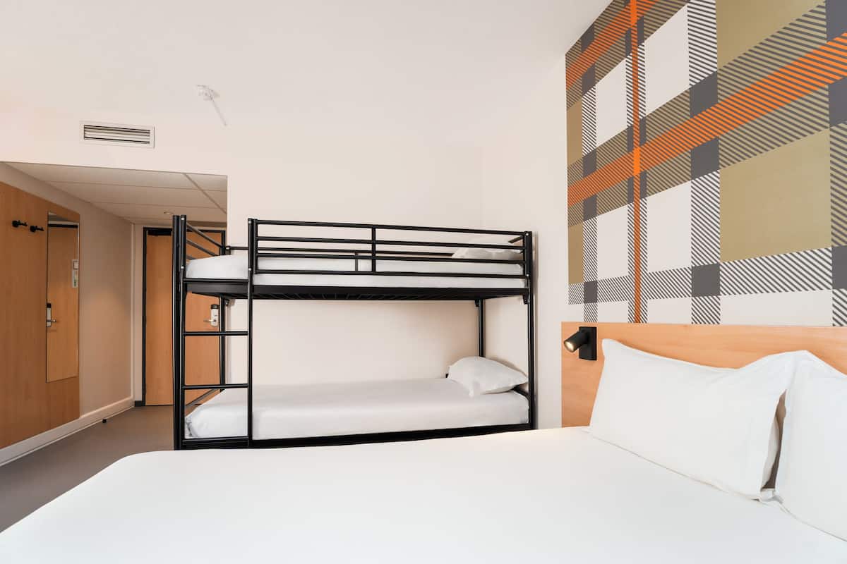 A bunk bed room with a wooden wardrobe, a door, and a patterned wall.