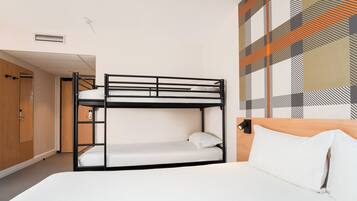 A bunk bed room with a wooden wardrobe, a door, and a patterned wall.