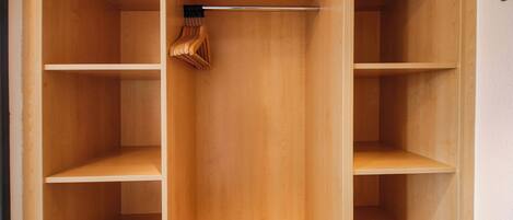A wooden closet with multiple shelves and hanging space.